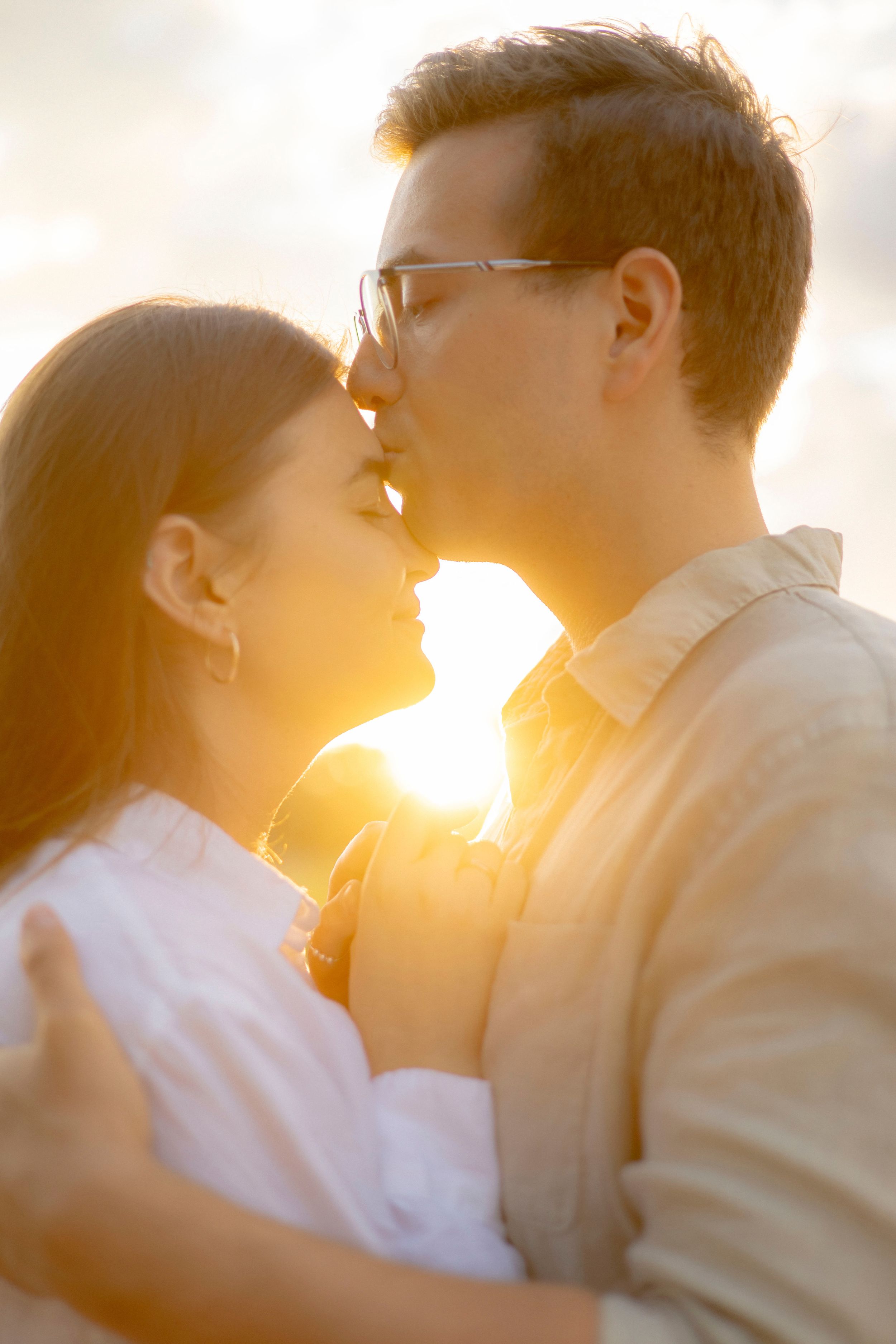 Tender romantic moment captured during golden sunset with sunflare.
