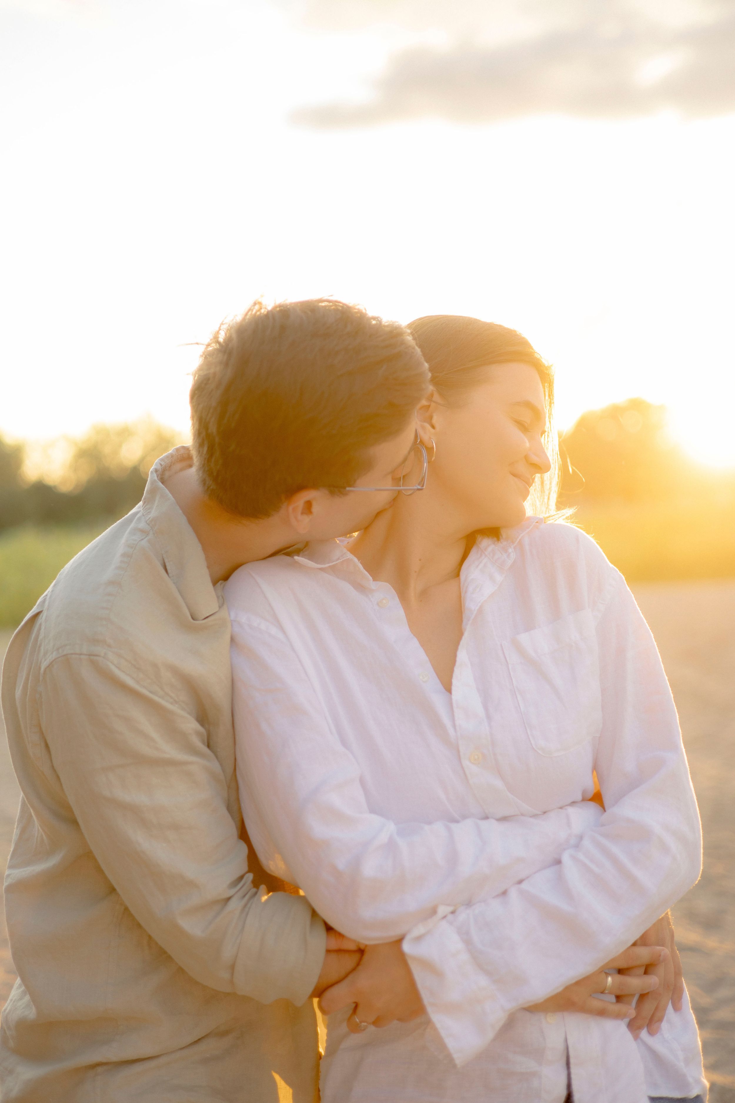 Intimate couple's portrait with warm sunset lighting in natural setting.