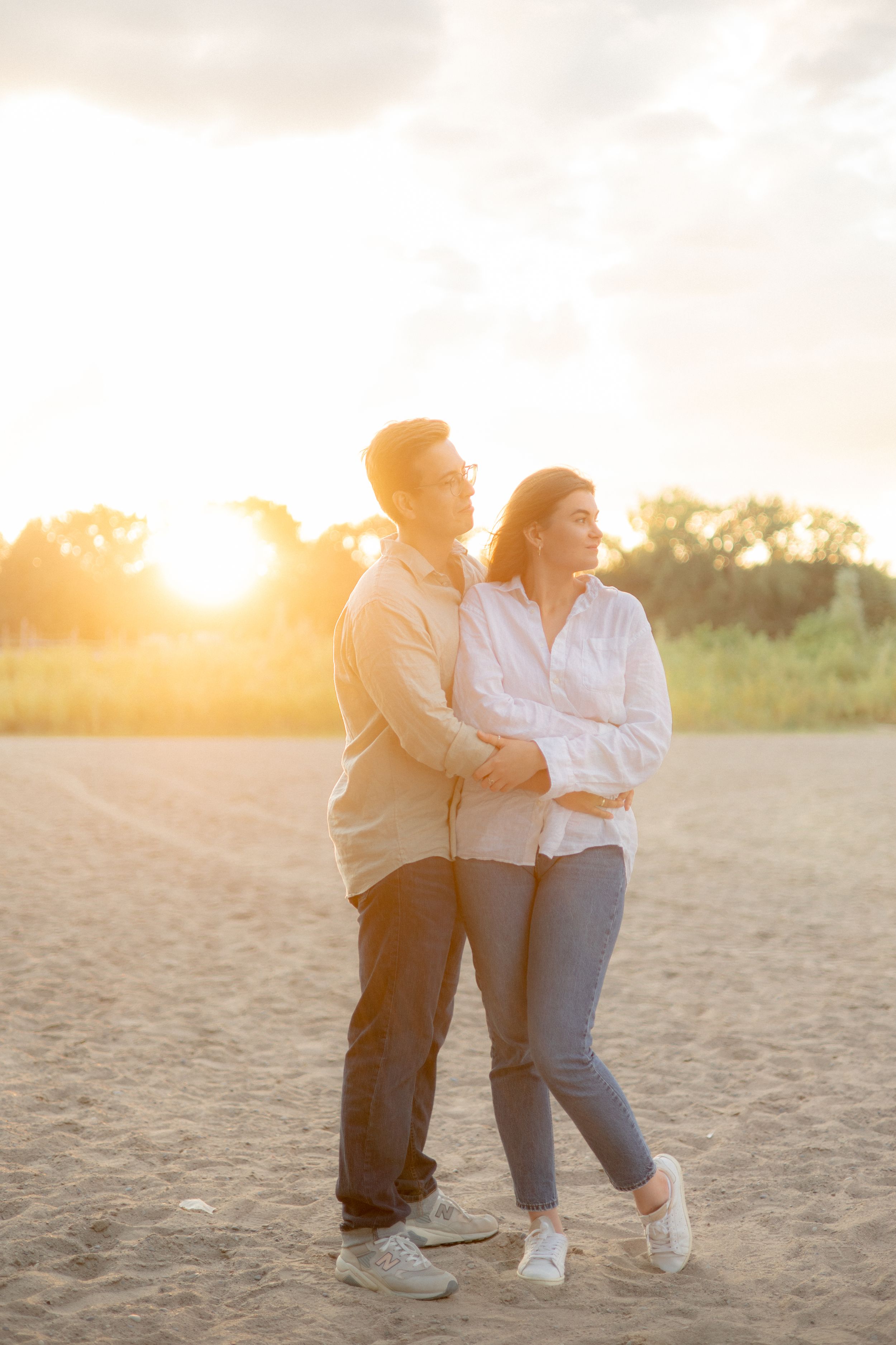 Couple in matching light colored shirts sharing moment at sunset.