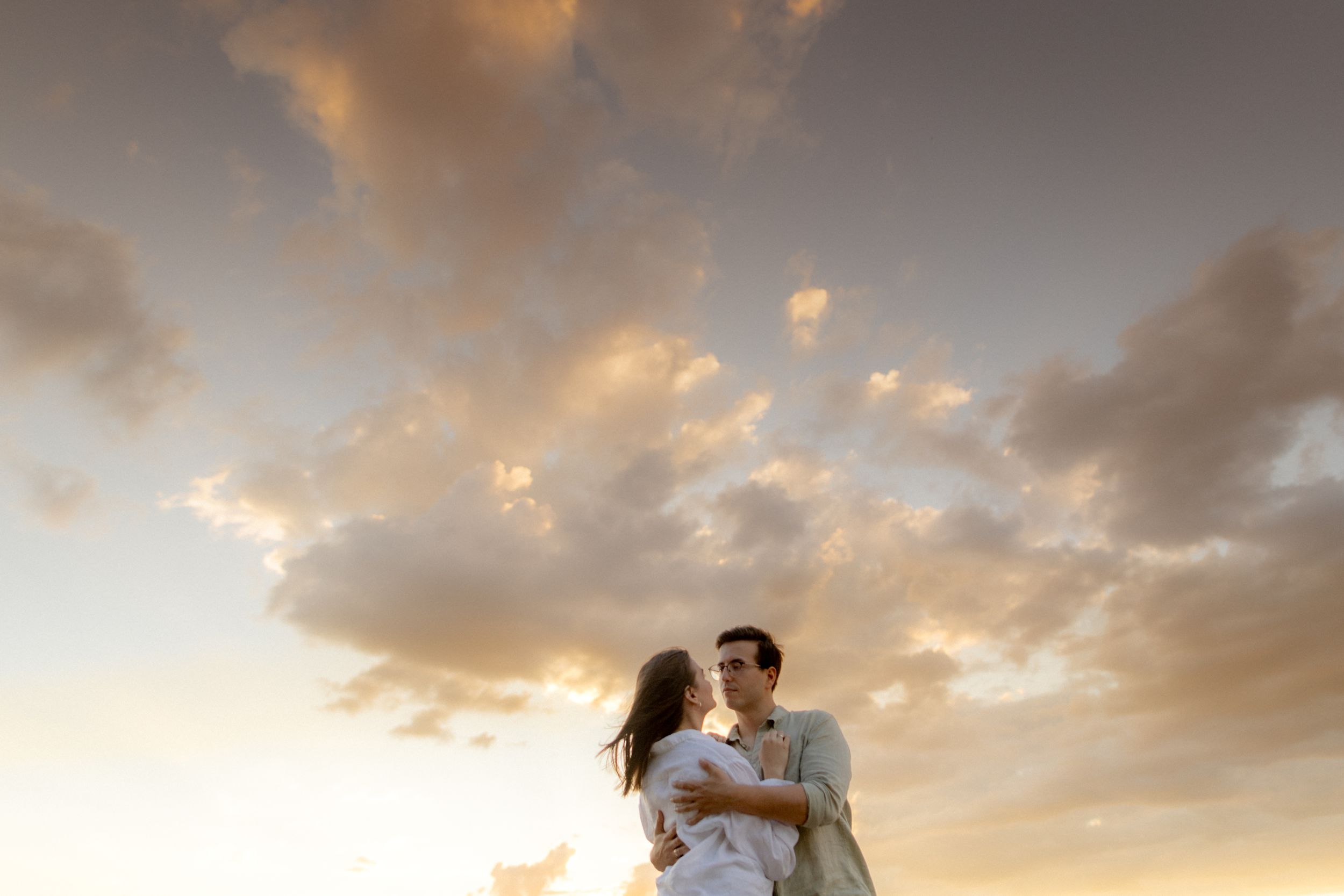 Romantic silhouette against dramatic sunset sky with clouds.