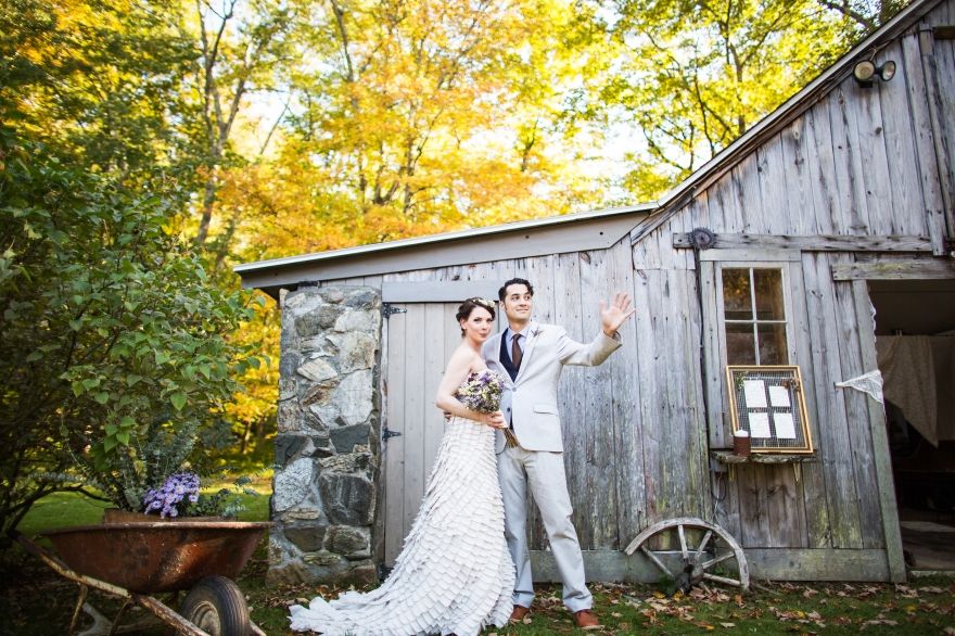 Newlyweds celebrating in front of rustic barn with fall colors.