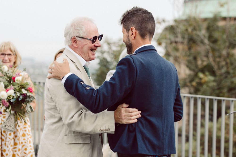 Wedding guests embrace and celebrate with joyful emotions during outdoor reception.