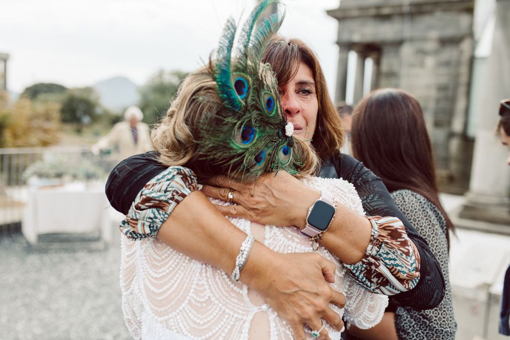 Guests share warm hugs and greetings at elegant outdoor wedding venue.