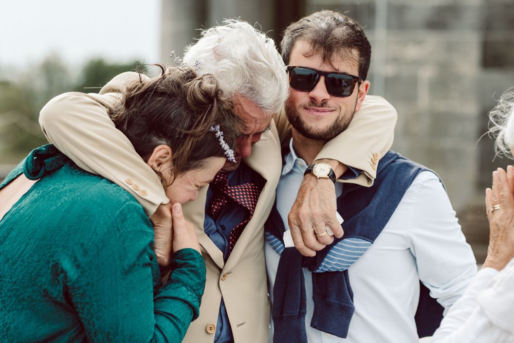 Joyful wedding celebration with guests embracing on stone terrace.