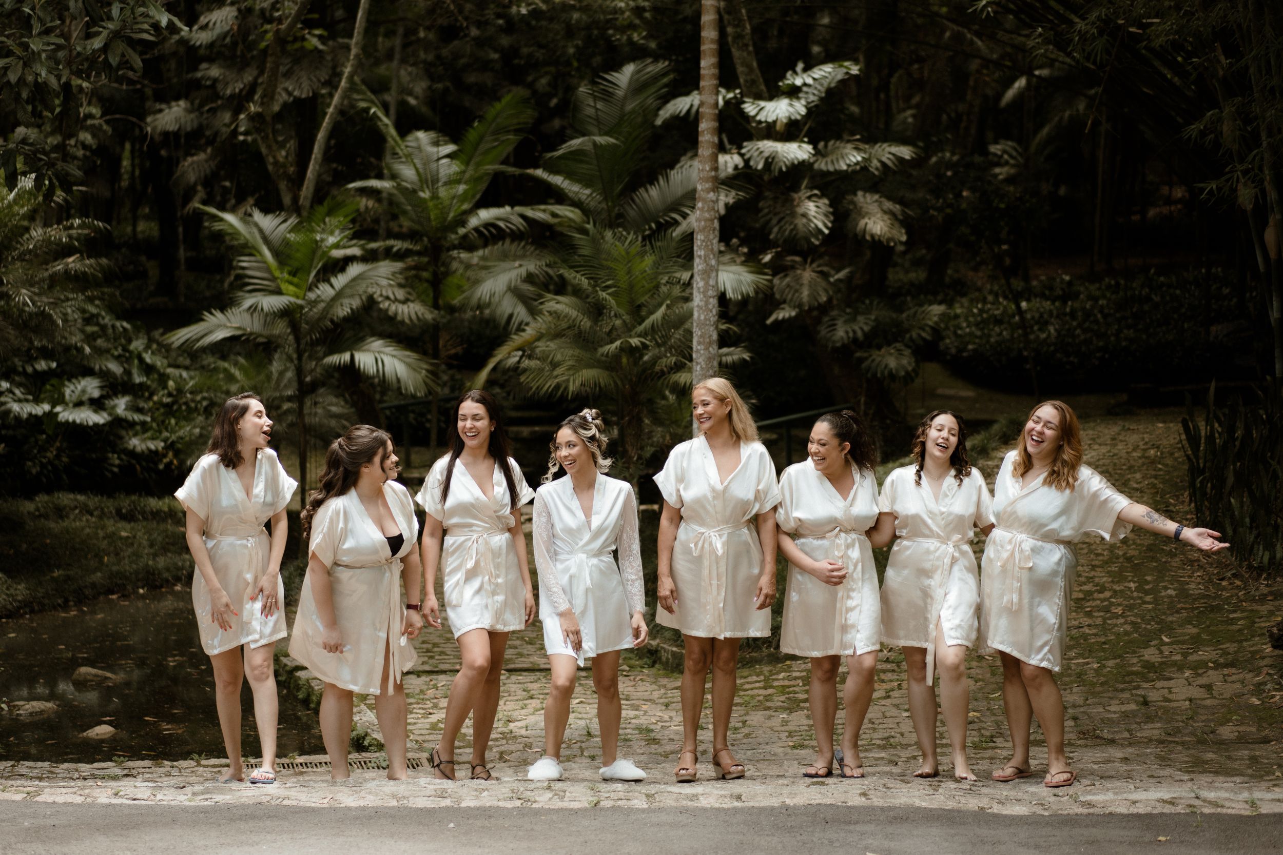 Group wearing white outfits poses together in a natural outdoor setting.