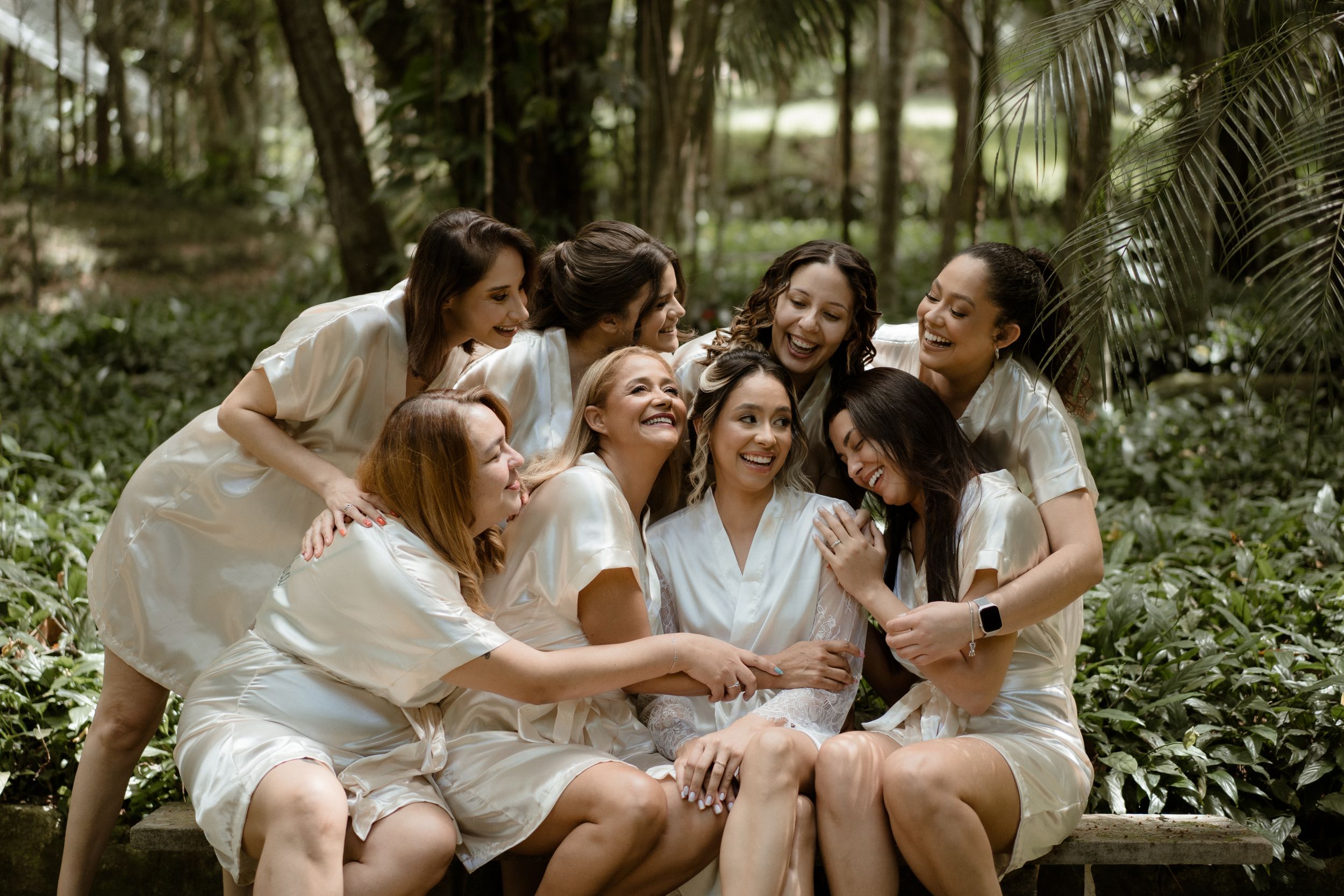 Friends in white attire sharing joyful moments in a garden setting.
