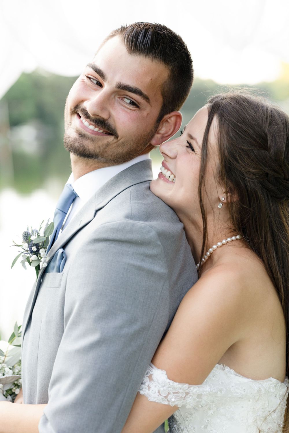 Newlyweds share joyful moments in grey and white attire during outdoor photoshoot.