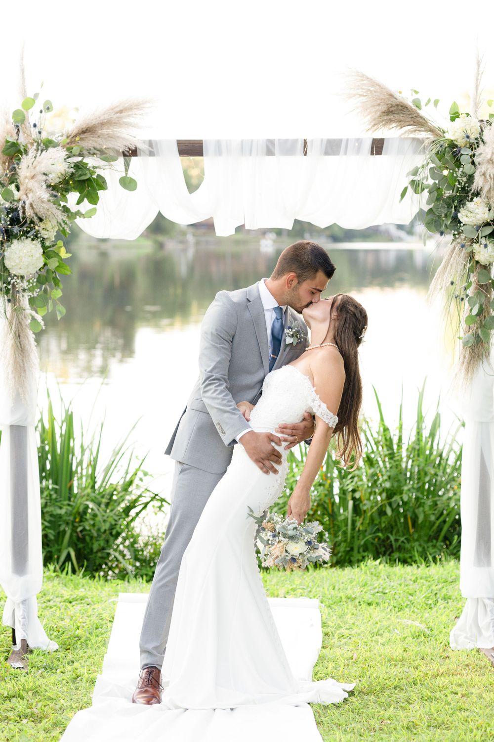 Wedding couple embraces during romantic lakeside photo session.