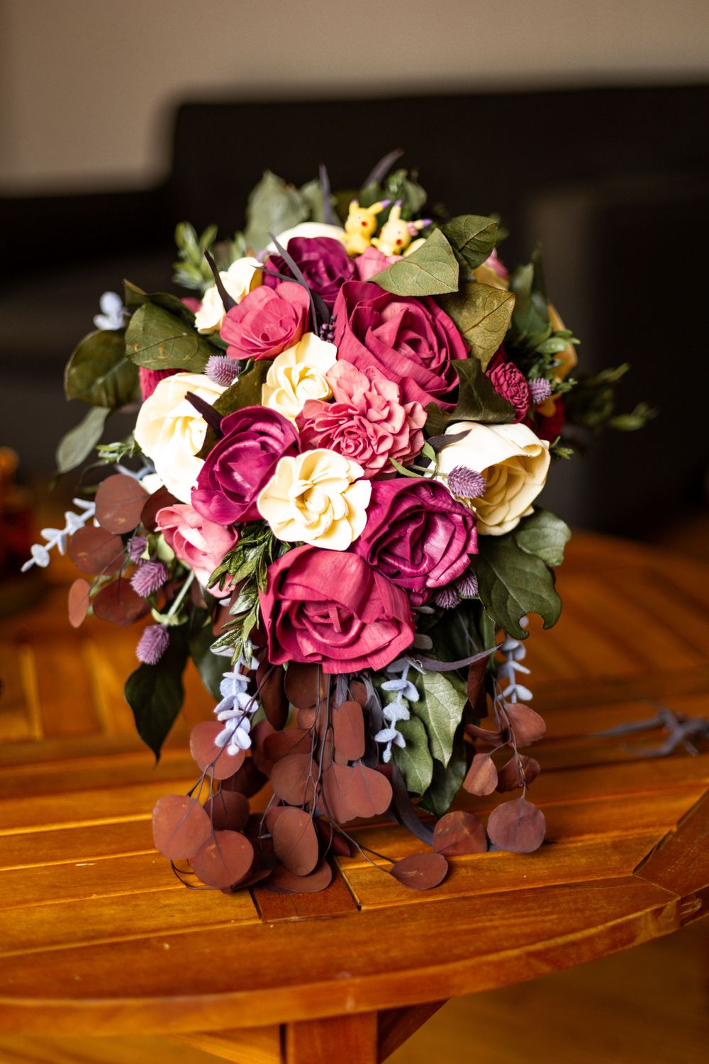 Beautiful floral arrangement with burgundy and cream roses on wooden surface.