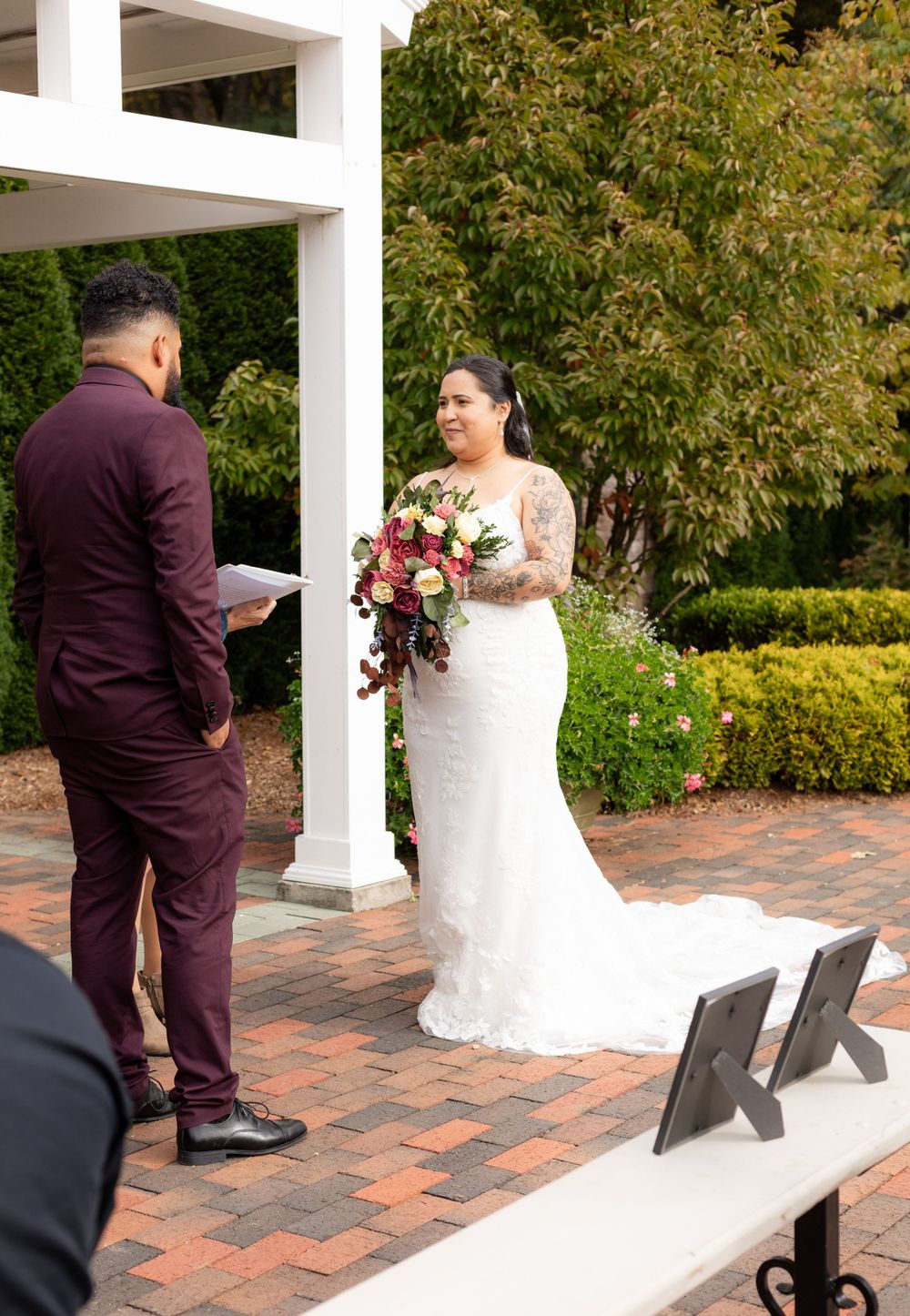 Wedding first look sequence on a brick patio with white columns and garden backdrop.