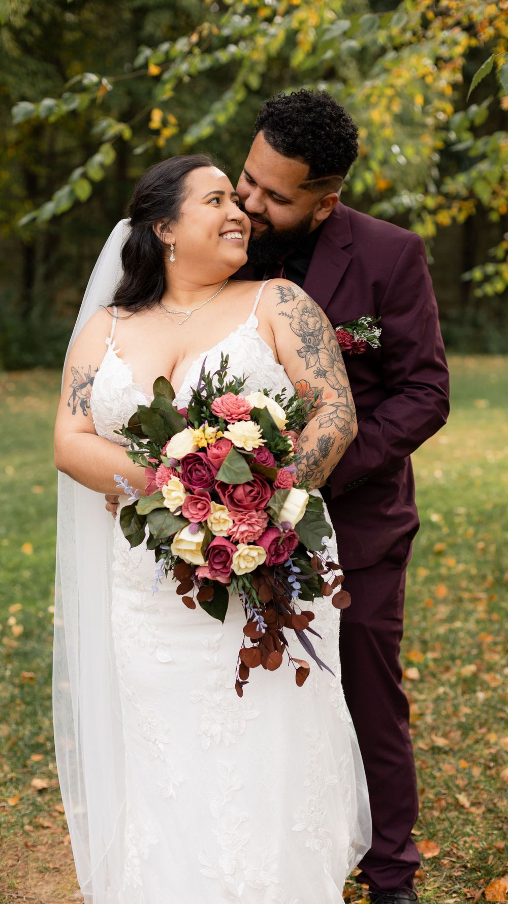 A romantic wedding photoshoot in an autumn garden with burgundy and white floral bouquet details.
