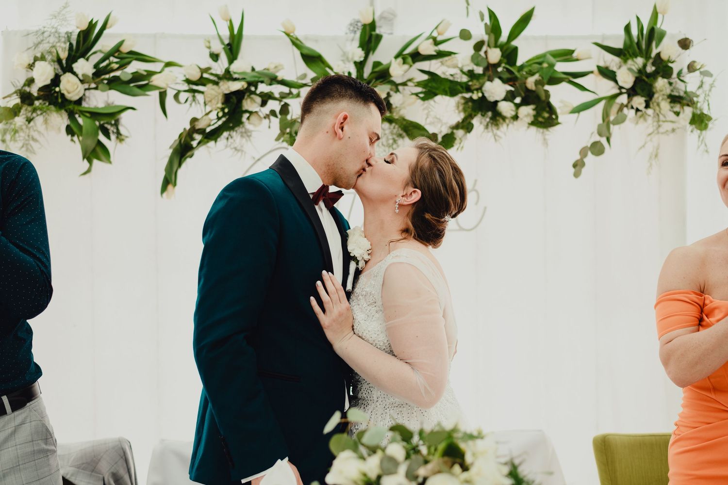 Wedding couple shares intimate moments in front of a floral arch during their outdoor ceremony.