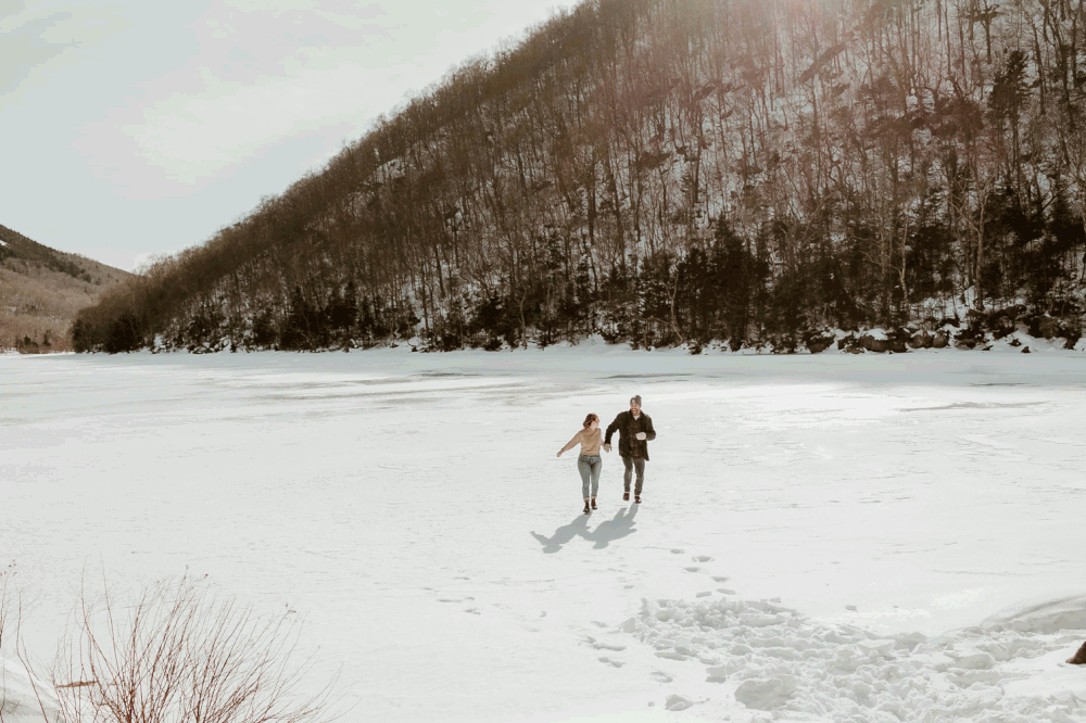 Couple running and playing in the snow in New Hampshire engagement photos