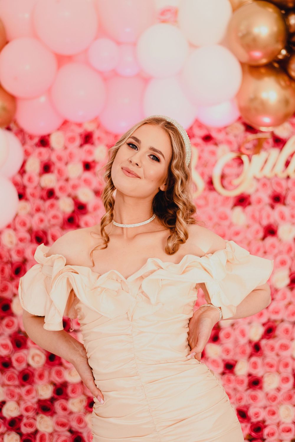Pink floral backdrop with decorative balloons creating a romantic party atmosphere.