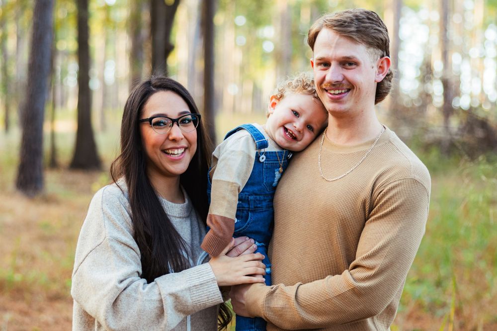 Family gathering outdoors in autumn forest setting for casual portrait session.