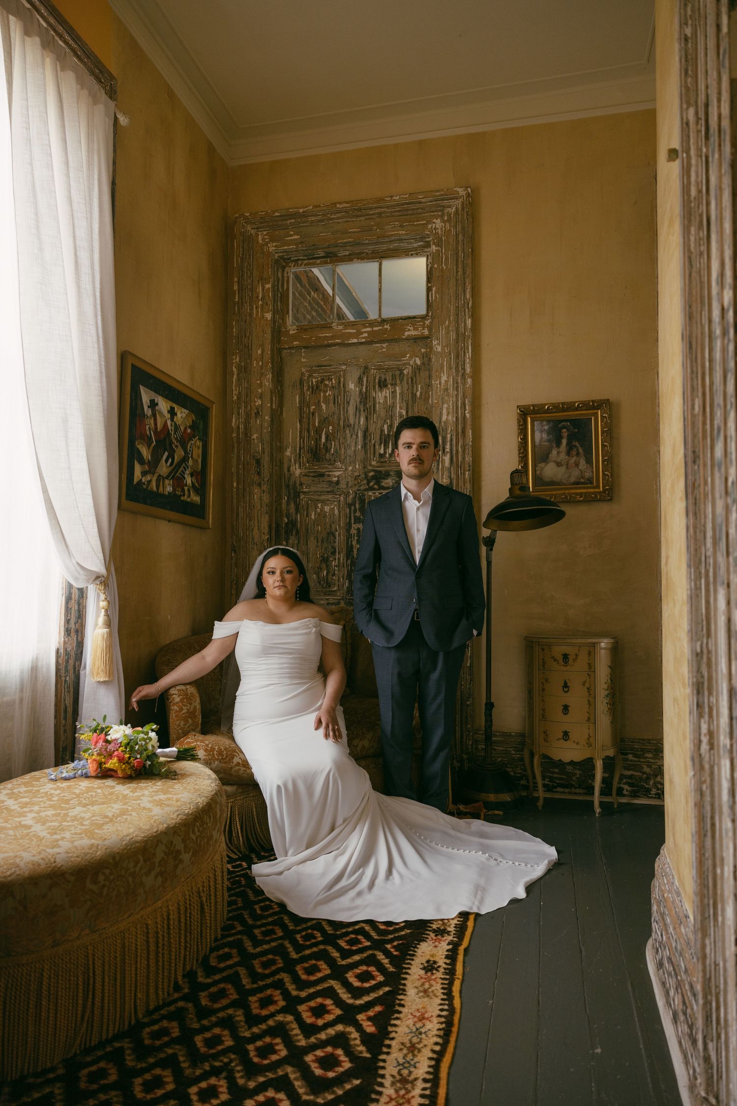 A candid moment between a couple sharing laughter against a grey curtain backdrop.