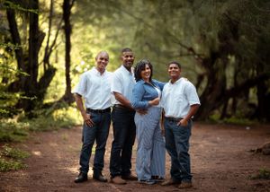 A group poses together on a tree-lined path wearing coordinated white and blue casual outfits.