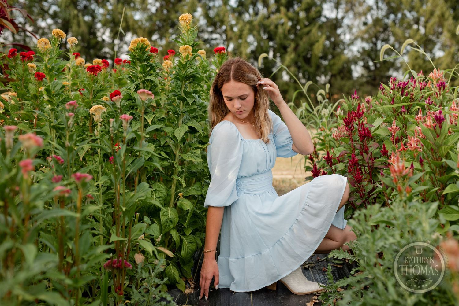 A gentle summer portrait in a blooming flower garden shows a light blue vintage-style dress.