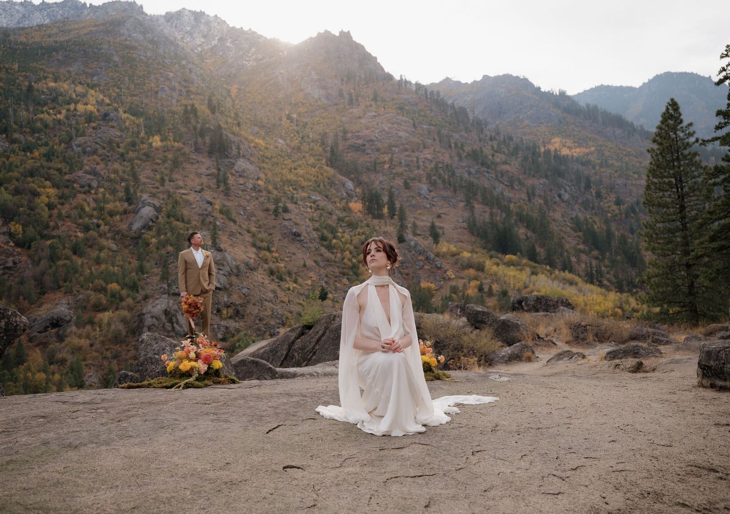 Panoramic mountain wedding ceremony setup with rustic wooden chairs and mountain peaks in the background.