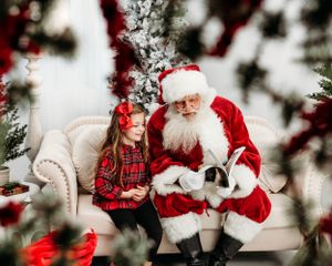 A cozy Christmas scene on a white sofa with festive decor and twinkling lights. Santa photographer