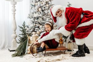 A joyful winter scene with a wooden sleigh and flocked Christmas tree in the background. Santa photographer