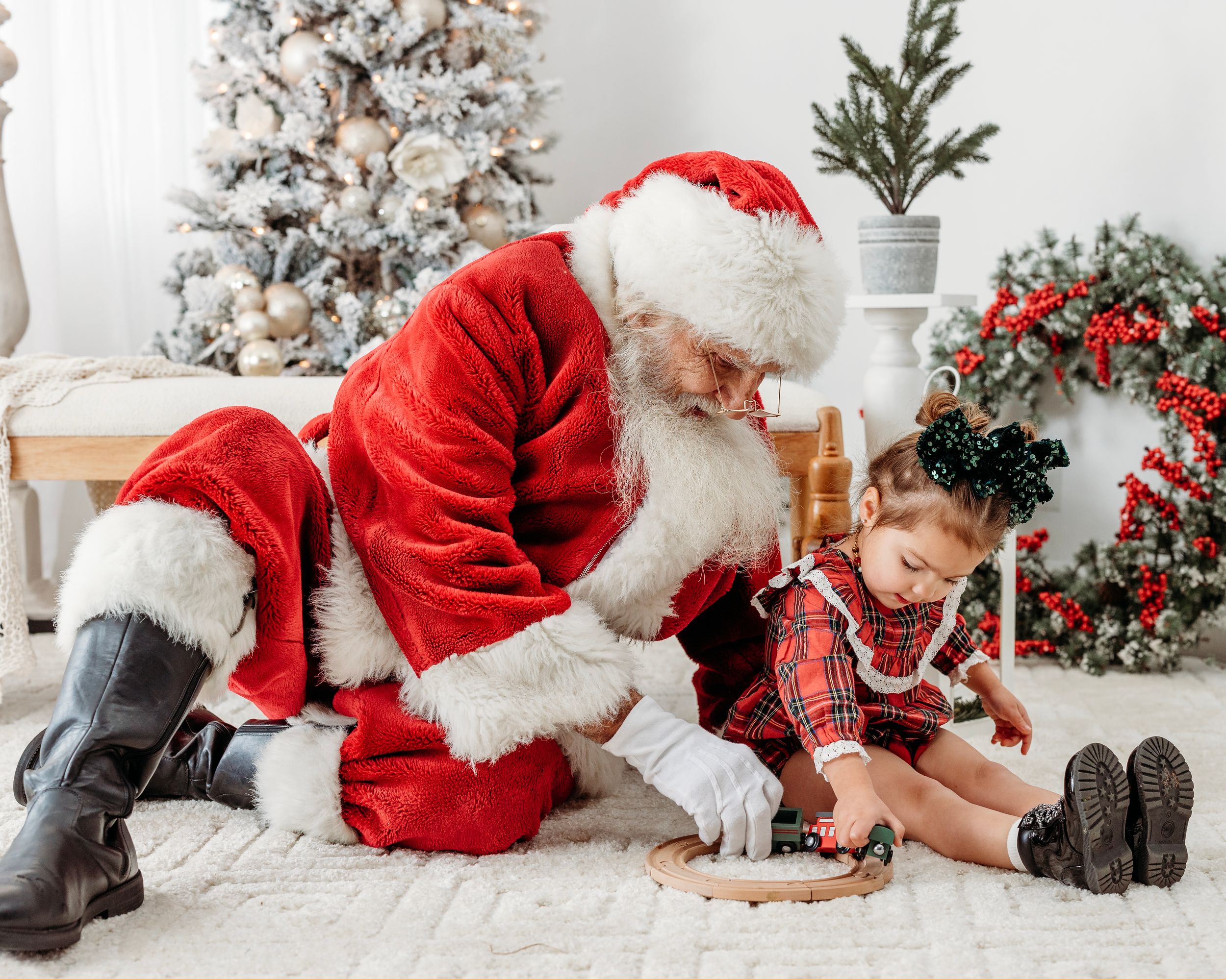 Christmas photo session on white carpet with flocked tree and holiday decor. Santa photographer