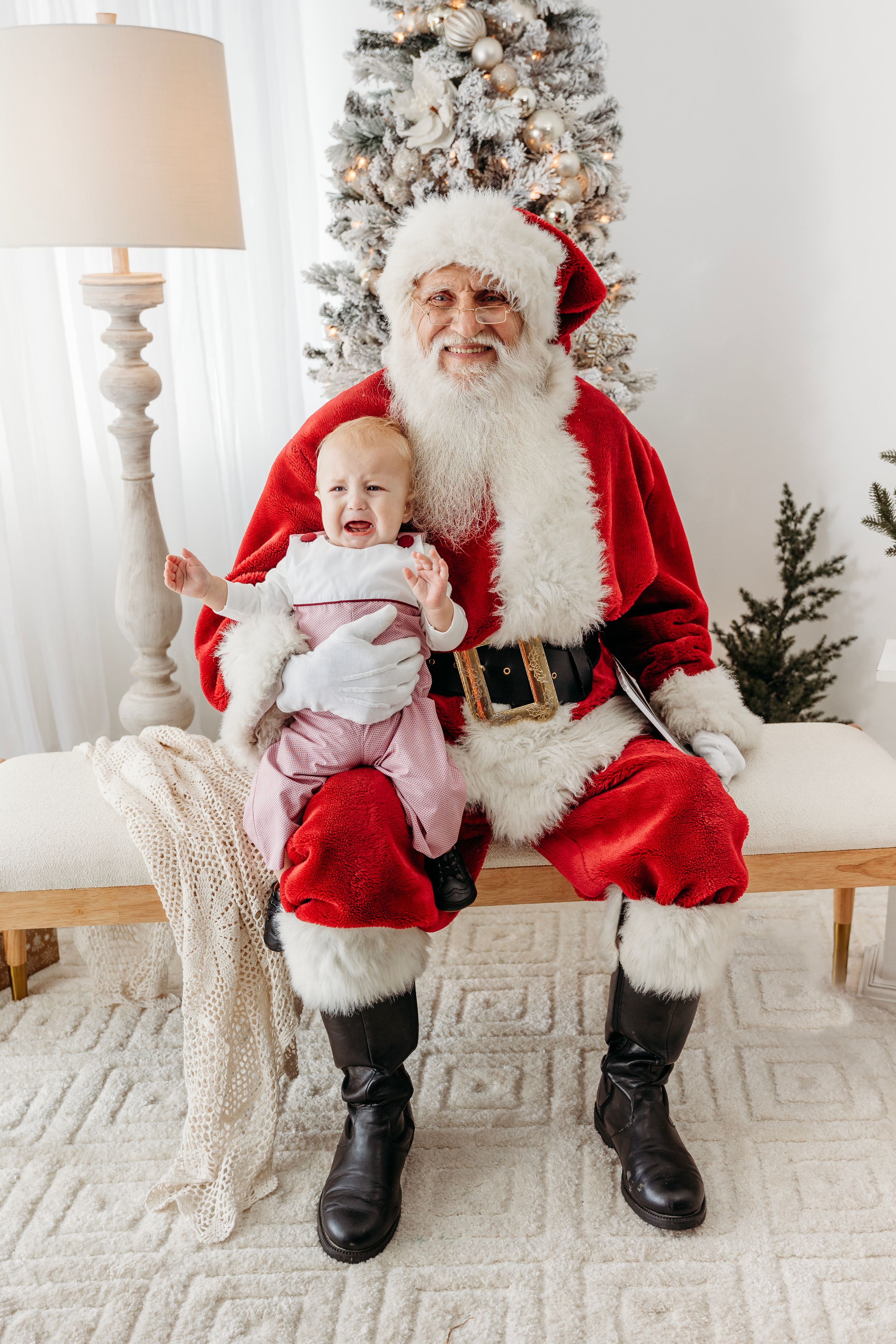 Holiday photo session in front of a flocked Christmas tree with white decor and candle holders. Santa photographer