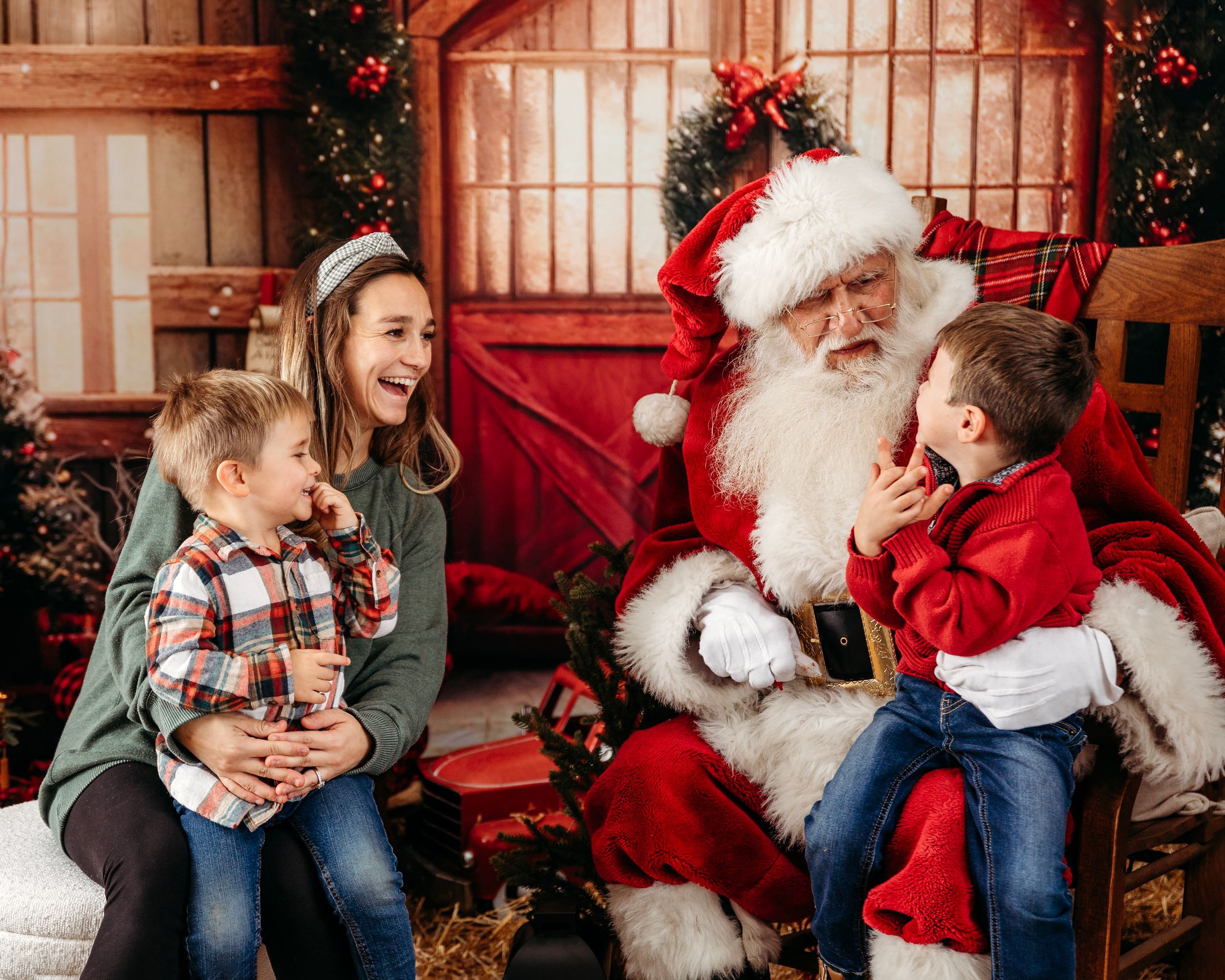 Holiday portraits in rustic barn setting with red and green Christmas decorations. Santa photographer
