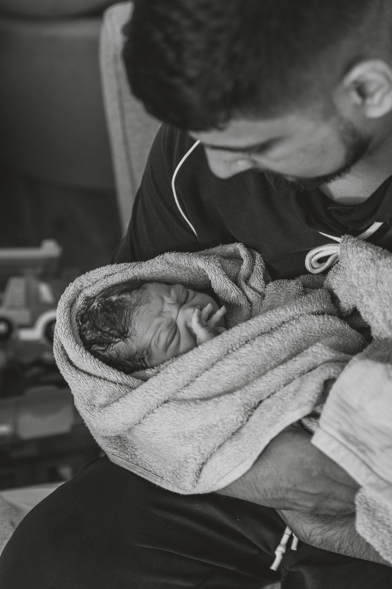 Black and white image of a newborn wrapped in a soft towel being cradled. Photographer. Hull. East Yorkshire. Photography