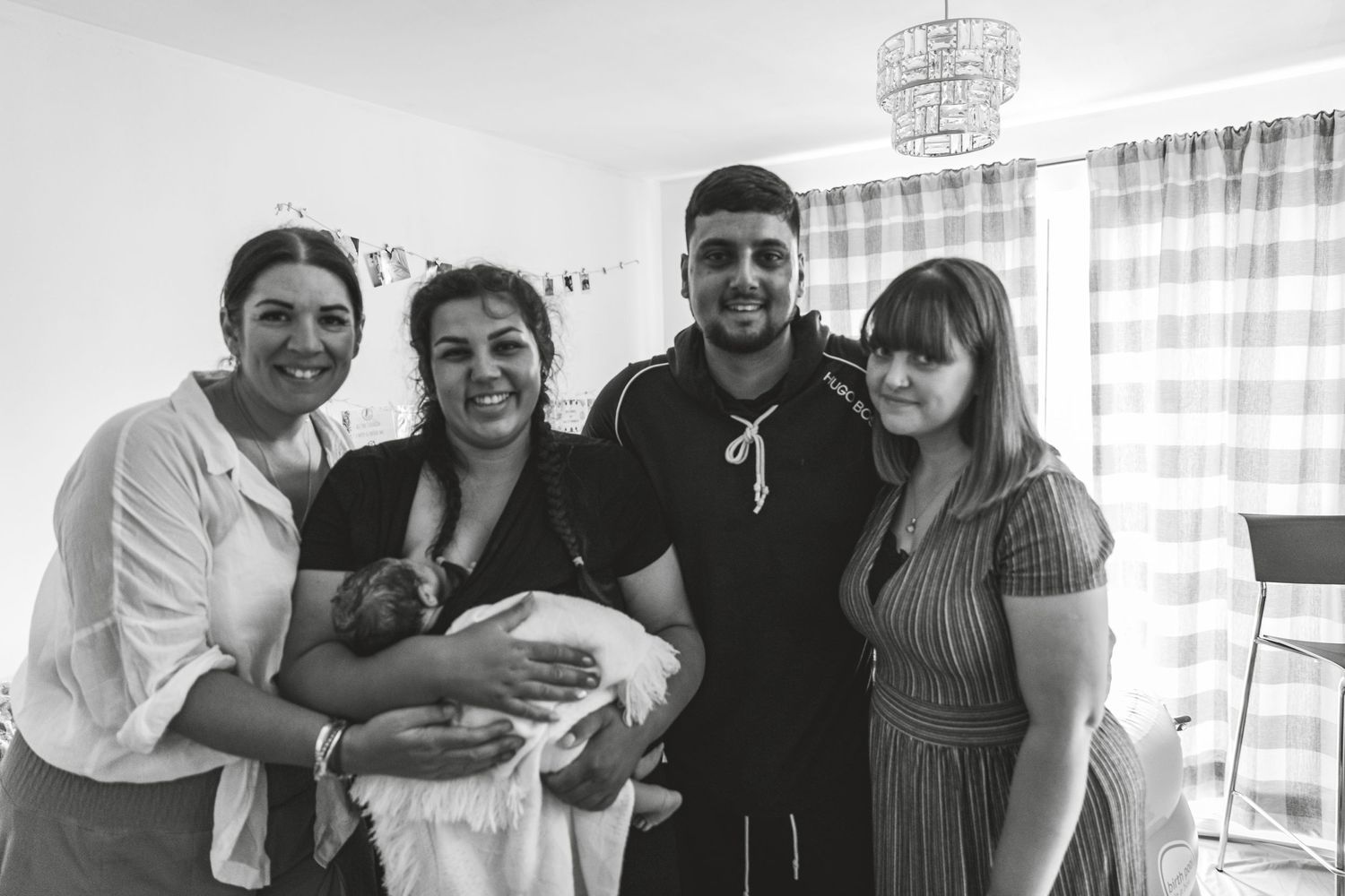 Group photo of family members holding and celebrating a newborn baby in a bright room. Photographer. Hull. East Yorkshire. Photography