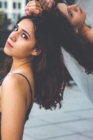 Artistic portrait showing flowing dark hair against an urban background.