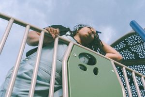 Low angle view of someone relaxing on playground equipment against blue sky.