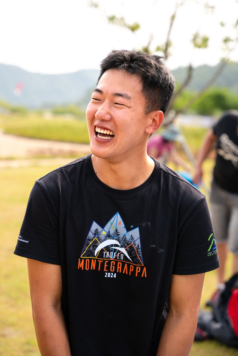 A person wearing a black t-shirt with mountain graphics outdoors.