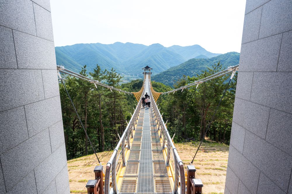 Long suspension bridge walkway stretching between mountains with scenic valley views.