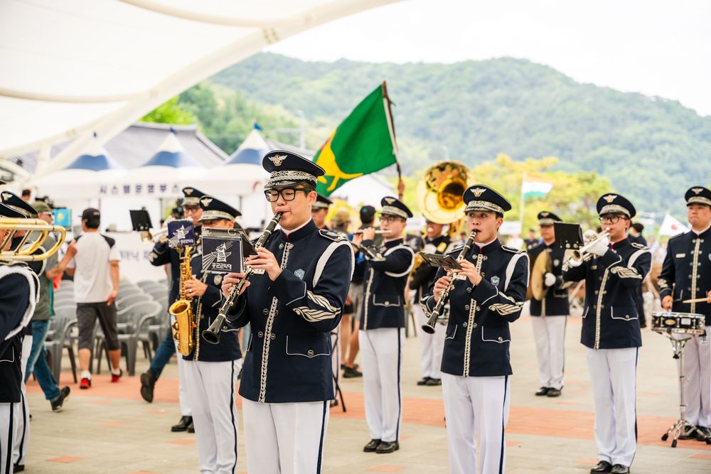 Marching band in navy and white uniforms performing at an outdoor event.