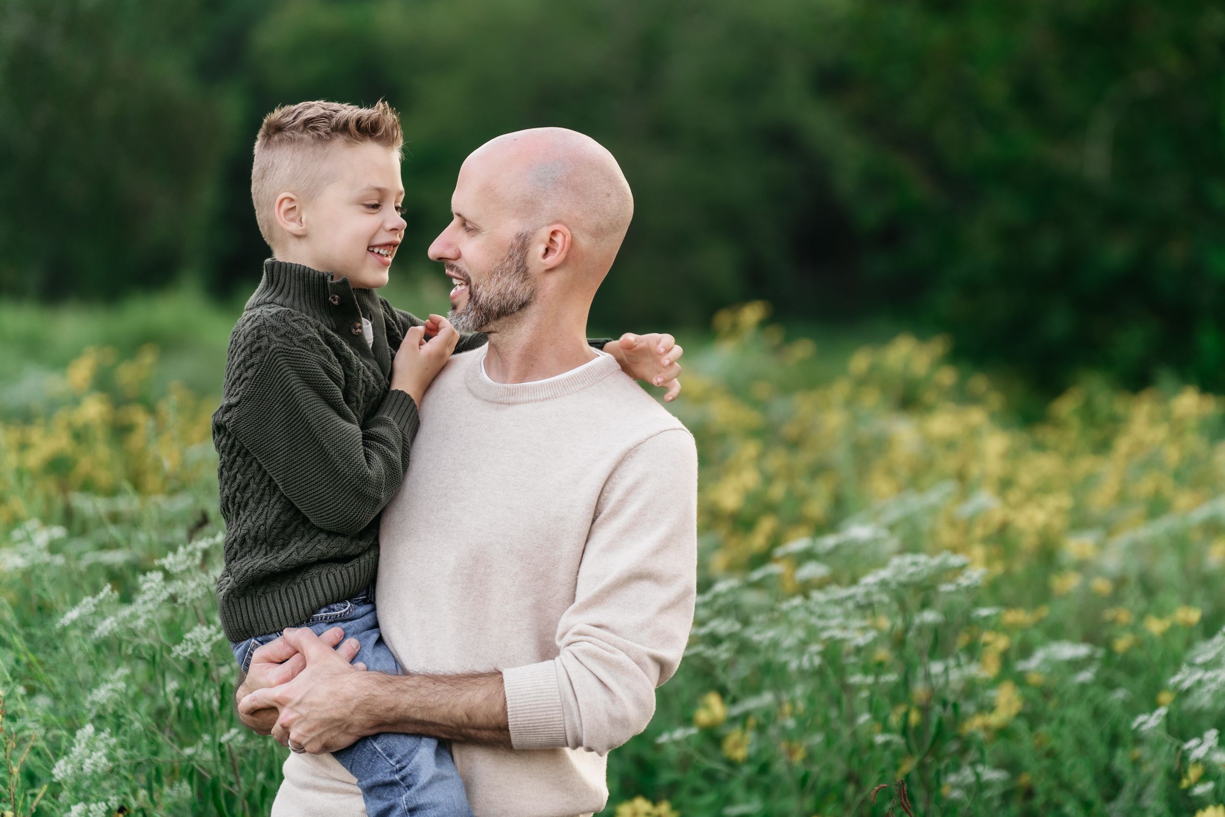Happy parent and child share affectionate moments in a blooming wildflower meadow in Cuyahoga Falls, Ohio for a family photo session