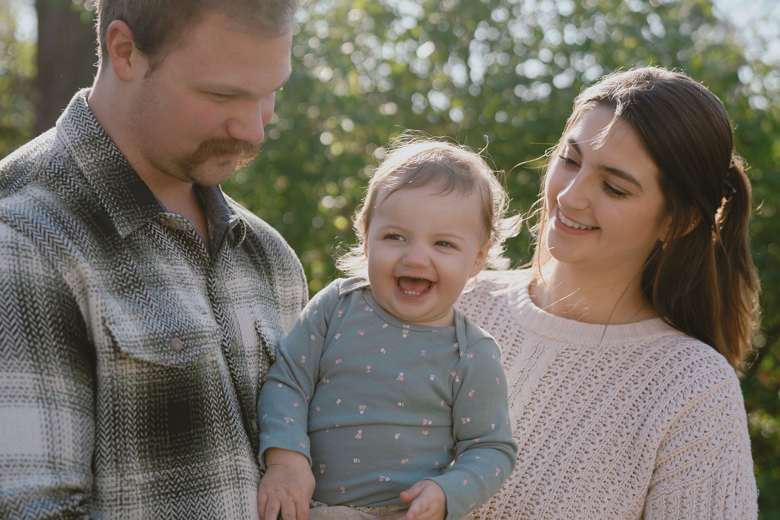 A family shares tender moments together in an outdoor autumn setting wearing coordinated casual attire in Marion, Ohio for family photos.