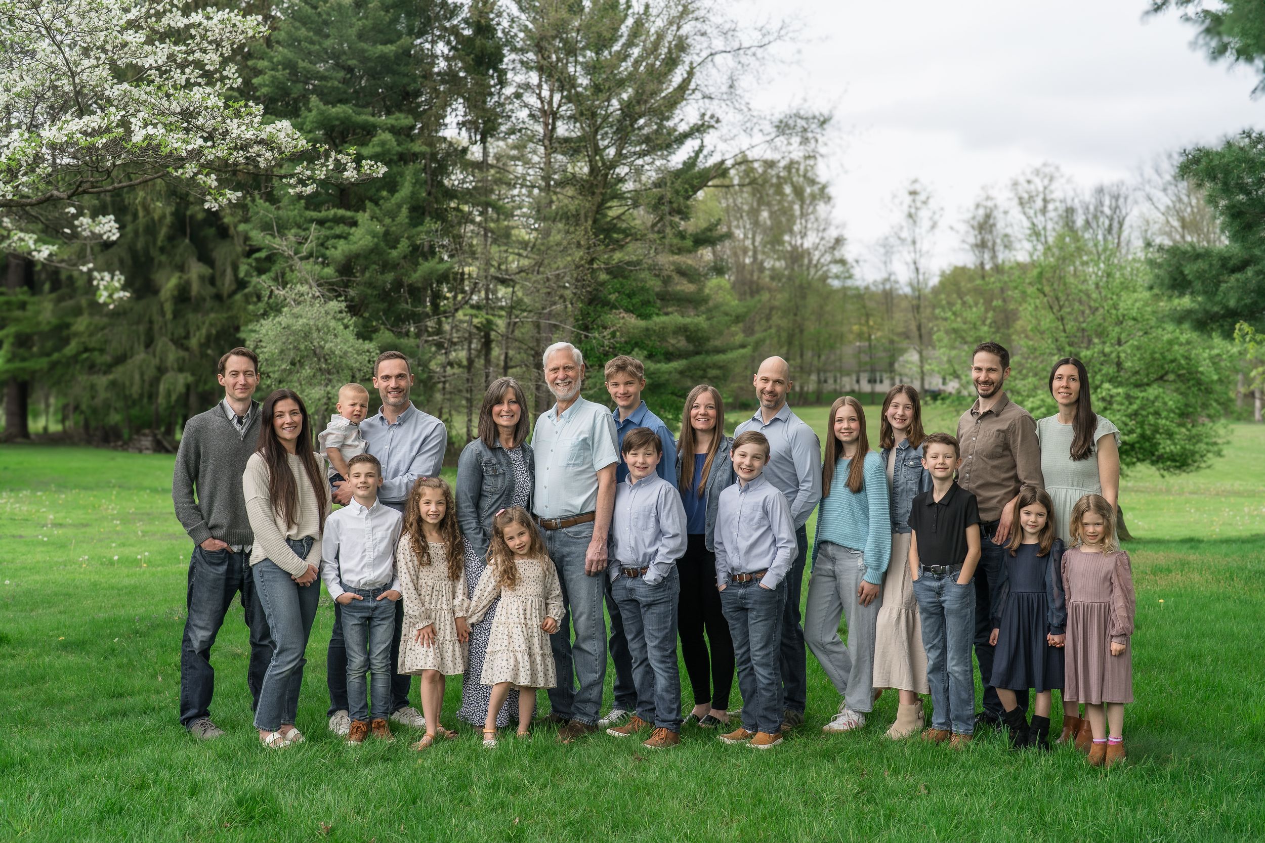 Family photo session showing a large group during an outdoor photo session in a grassy field with trees in Stow, Ohio
