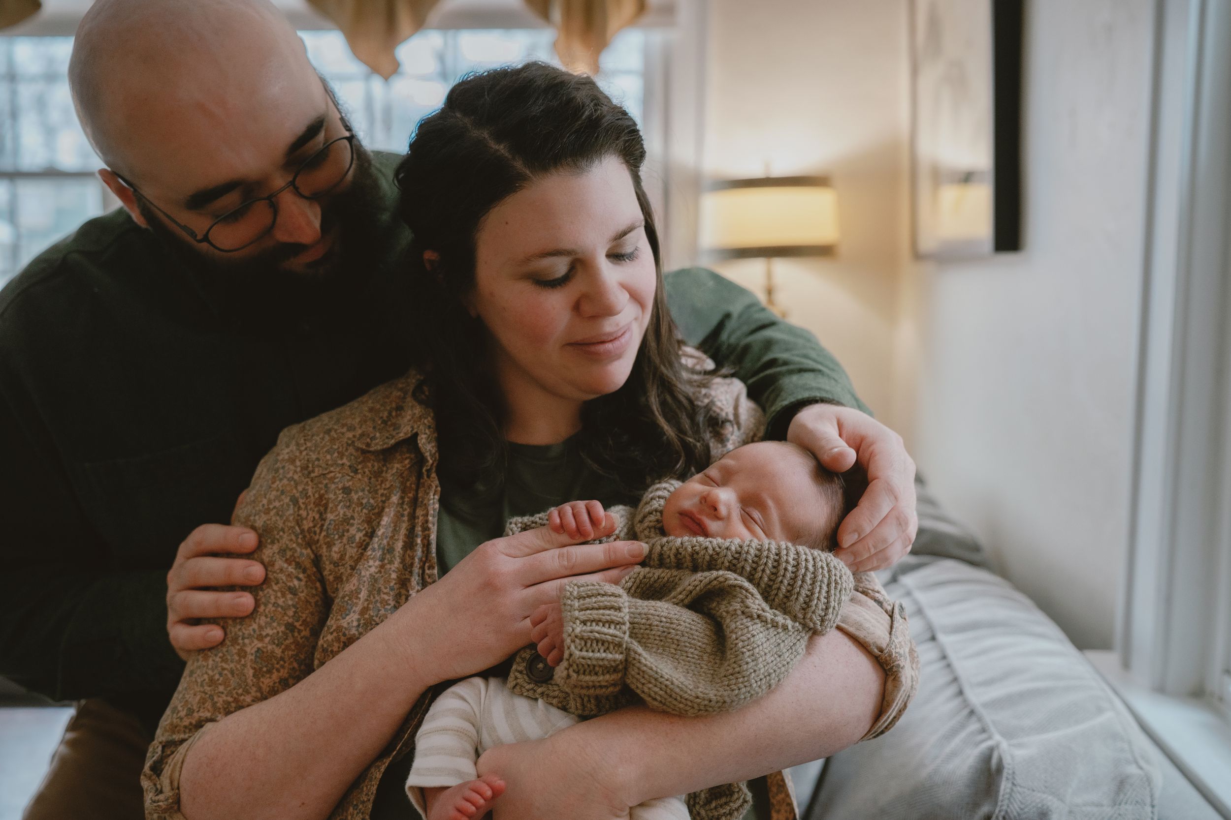 Parents lovingly embrace their newborn baby in a series of tender moments at home in Stow, Ohio for newborn photos.