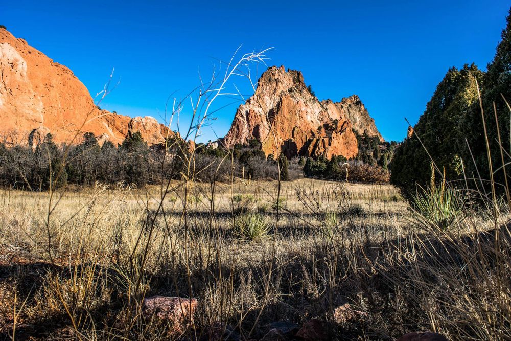 Dramatic red rock formations in Garden of the Gods with blue sky and winter vegetation.