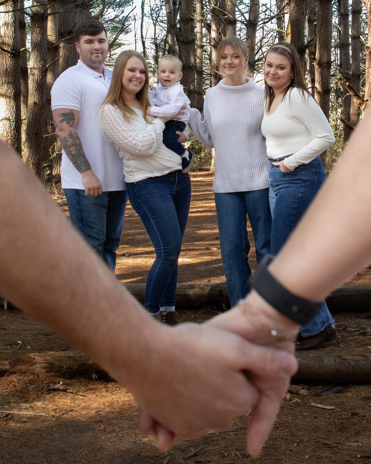 Family photo session in a pine forest with casual matching outfits.