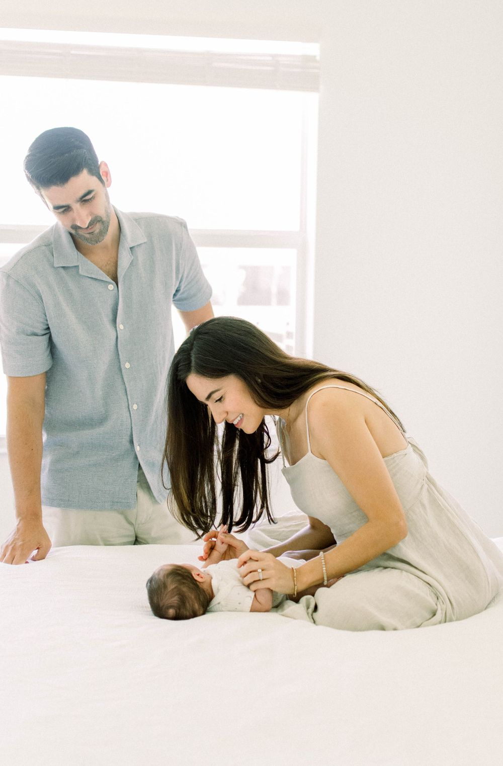 Parents sharing special moment with their newborn baby on white floor.