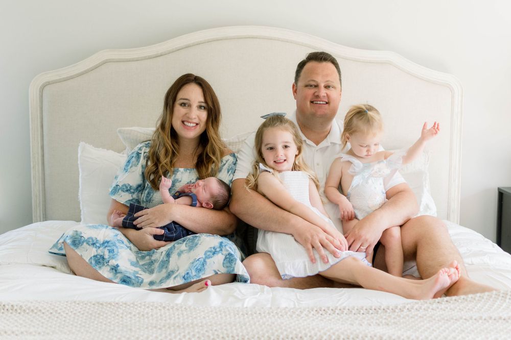 Family of five gathered together on white bed for intimate portrait session.