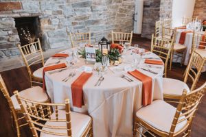 Reception venue with stone walls and white round tables elegantly set for dinner.