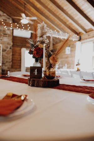 Rustic wedding centerpiece with roses on wooden slice and table number 4.