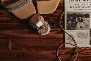 Vintage newspaper and brown leather shoes on rustic wooden table with warm lighting.