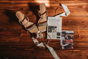 Sandals and vintage newspaper clippings arranged on dark wood surface.