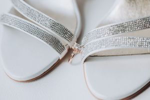 White wedding sandals with sparkling rhinestone straps displayed on a light background.