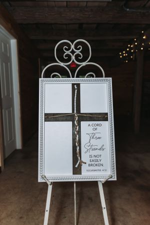White decorative easel displaying religious scripture quote with cross design.