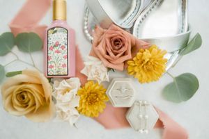 Wedding detail flatlay with roses, perfume bottle and eucalyptus leaves.